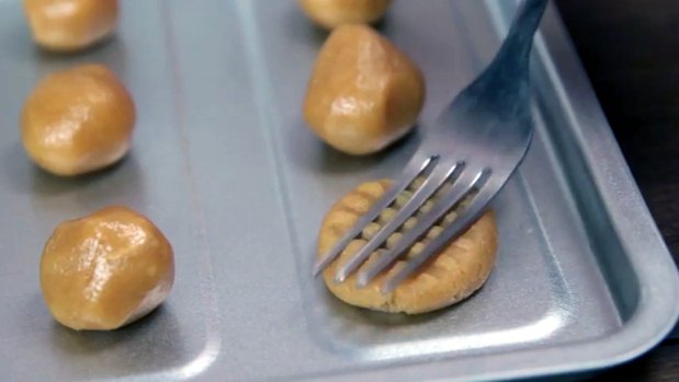 Após fazer as bolinhas da 'massa' e colocar na assadeira, que não precisa ser untada, use um garfo para 'achatá-las' em dois sentidos diferentes, para dar um acabamento diferenciado(foto: BuzzFeed/Reprodução) Após fazer as bolinhas da 'massa' e colocar na assadeira, que não precisa ser untada, use um garfo para 'achatá-las' em dois sentidos diferentes, para dar um acabamento diferenciado(foto: BuzzFeed/Reprodução)