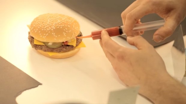 O hambúrguer criado em estúdio para a sessão de fotos é montado 'cirurgicamente' de forma a deixar visíveis todos os seus ingredientes(foto: YouTube/Reprodução) O hambúrguer criado em estúdio para a sessão de fotos é montado 'cirurgicamente' de forma a deixar visíveis todos os seus ingredientes(foto: YouTube/Reprodução)